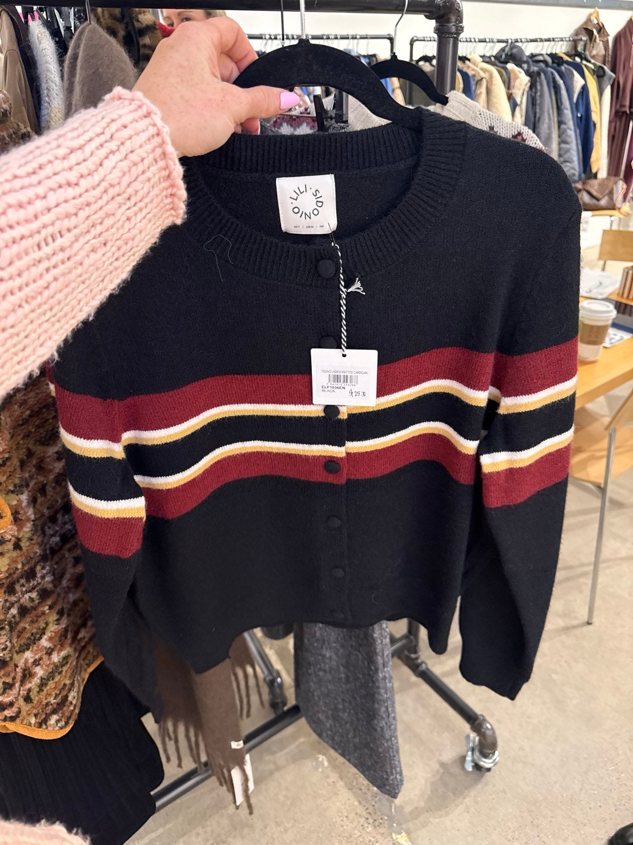 Black knitted cardigan with burgundy, white, and gold stripes, button-front, cropped fit on hanger