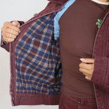 Burgundy flannel-lined denim bomber jacket shown open, revealing blue plaid interior lining, styled with matching trousers.