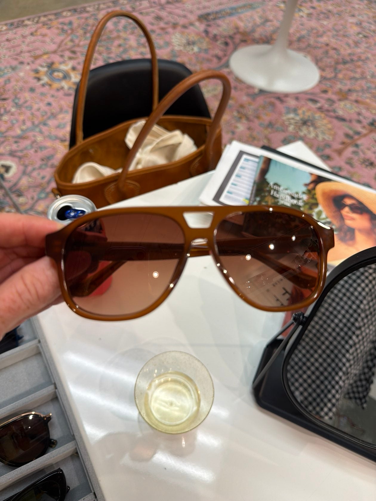 Hand holding oversized caramel brown aviator sunglasses with warm brown gradient lenses and gold hardware